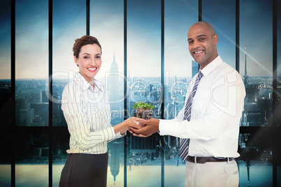 Composite image of business colleagues holding plant and looking