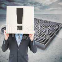 Composite image of businessman hiding head with a box