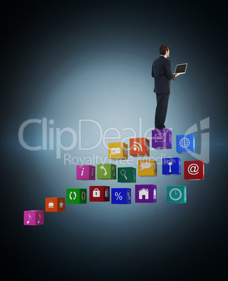 Composite image of handsome businessman standing using a laptop
