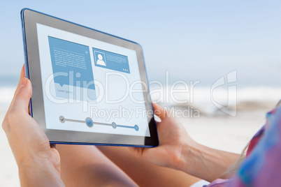 Composite image of woman sitting on beach in deck chair using ta Composite image of woman sitting on beach in deck chair using ta