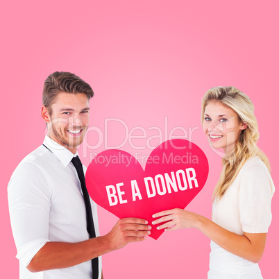 Composite image of attractive young couple holding red heart