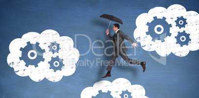 Composite image of businessman jumping holding an umbrella