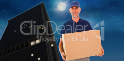 Composite image of happy delivery man holding cardboard box