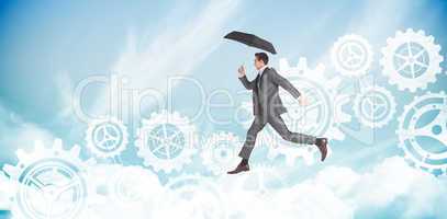 Composite image of businessman jumping holding an umbrella