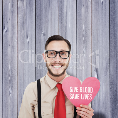 Composite image of geeky hipster smiling and holding heart card