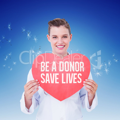 Composite image of smiling doctor holding heart card