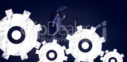 Composite image of businessman walking and holding umbrella