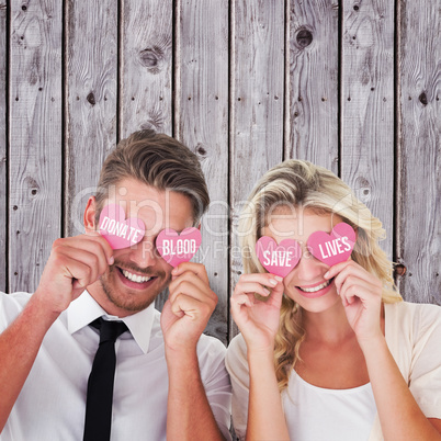 Composite image of attractive young couple holding pink hearts o