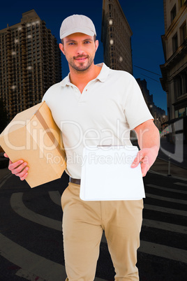 Composite image of delivery man with cardboard box showing clipb