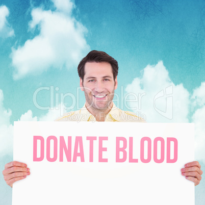 Composite image of attractive man smiling and holding poster