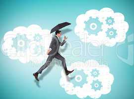 Composite image of businessman jumping holding an umbrella