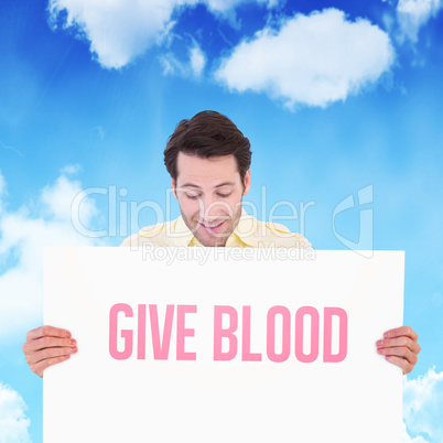 Composite image of attractive man smiling and holding poster