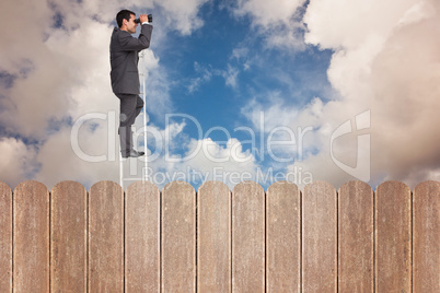 Composite image of businessman standing on ladder using binocula