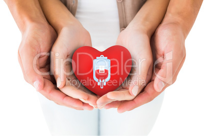 Composite image of couple holding miniature heart in hands