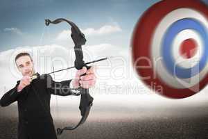 Composite image of concentrated businessman shooting a bow and a