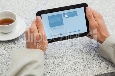 Composite image of businessman holding small tablet at table