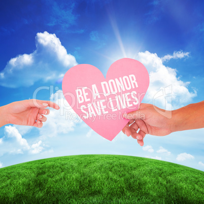 Composite image of couple passing a paper heart