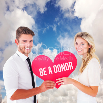 Composite image of attractive young couple holding red heart