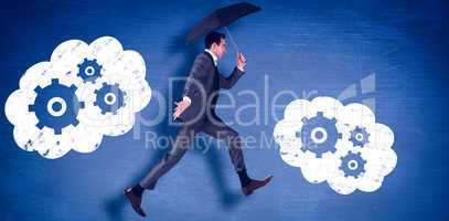 Composite image of businessman jumping holding an umbrella