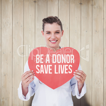 Composite image of smiling doctor holding heart card