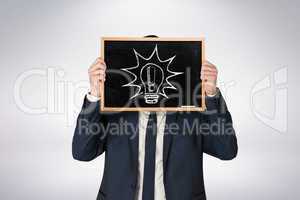 Composite image of businessman holding board