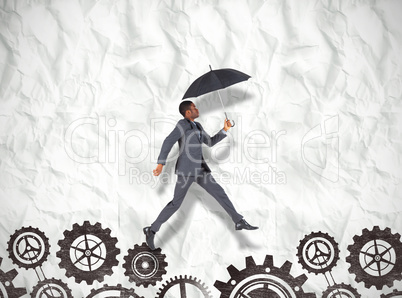Composite image of businessman walking and holding umbrella