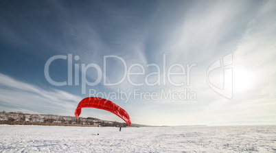 Kiteboarder with blue kite on the snow