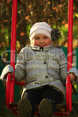 little girl plays on the swing