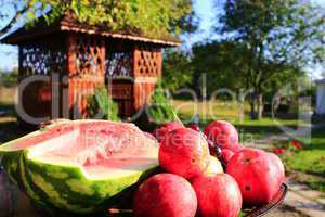 red apples and cut water-melon on the arbor background