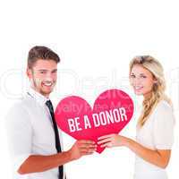 Composite image of attractive young couple holding red heart