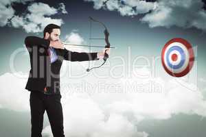 Composite image of focused businessman shooting a bow and arrow