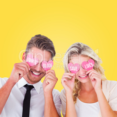 Composite image of attractive young couple holding pink hearts o