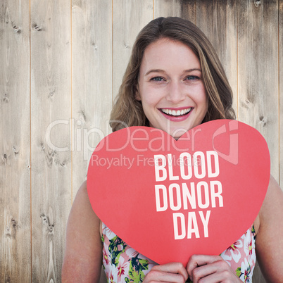 Composite image of woman holding heart card