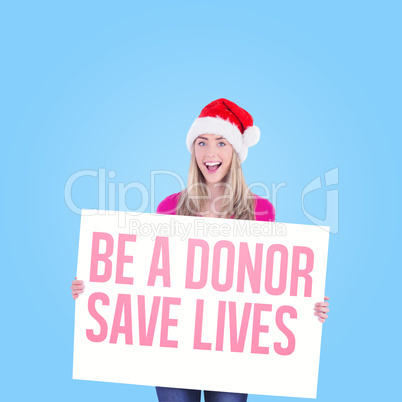 Composite image of festive blonde holding large poster