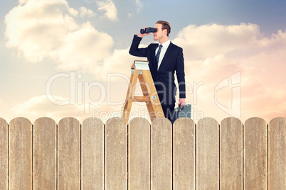 Composite image of businessman looking on a ladder