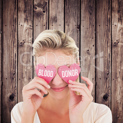 Composite image of attractive young blonde holding hearts over e