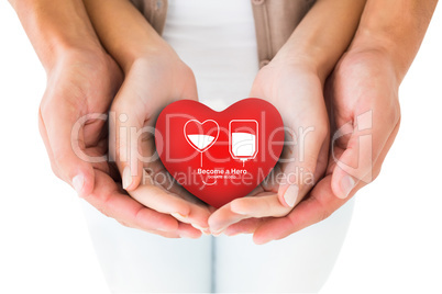 Composite image of couple holding miniature heart in hands