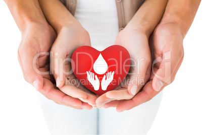 Composite image of couple holding miniature heart in hands