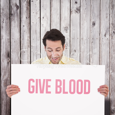 Composite image of attractive man smiling and holding poster