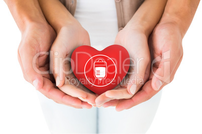 Composite image of couple holding miniature heart in hands