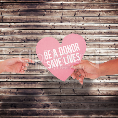 Composite image of couple passing a paper heart