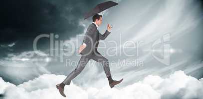 Composite image of businessman jumping holding an umbrella