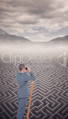 Composite image of businessman looking on a ladder