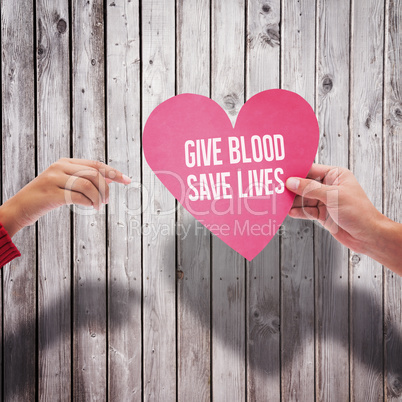 Composite image of couple holding a heart