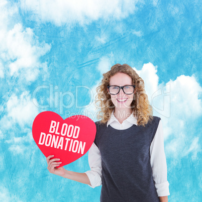 Composite image of geeky hipster holding heart card