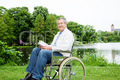 Man with wheelchair and tablet PC in the park