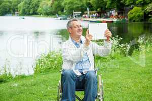 Man with wheelchair and tablet PC in the park