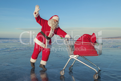 Santa Claus carries a shopping cart with gifts in a sack