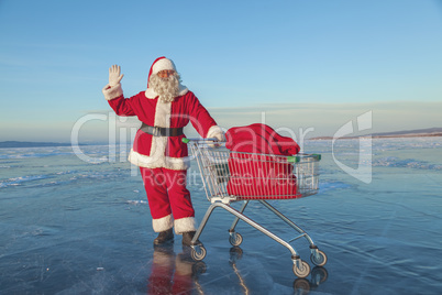 Santa Claus carries a shopping cart with gifts in a sack