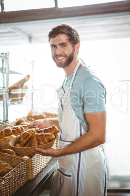 happy worker holding a basket of croissant